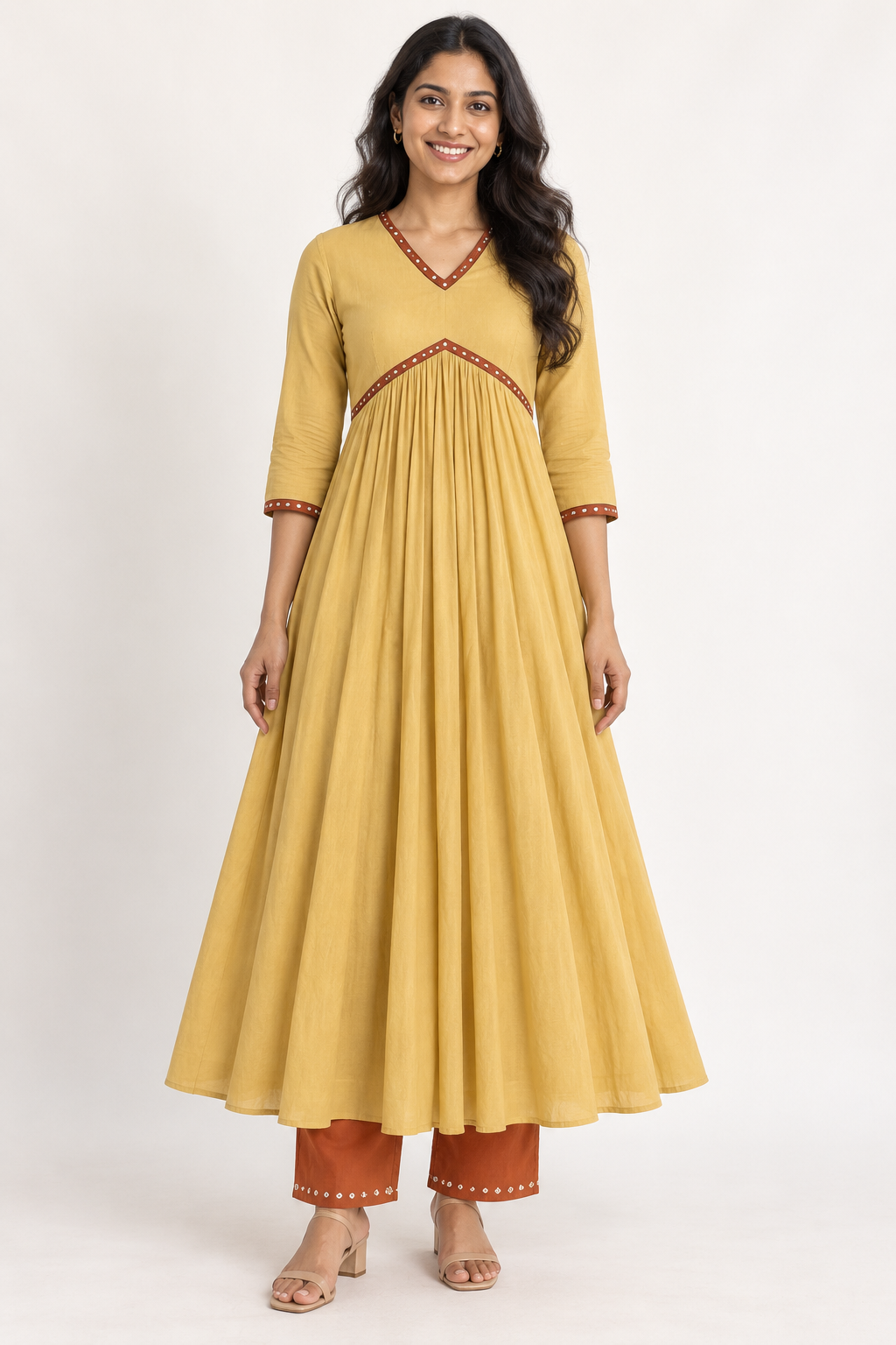Smiling model wearing a mustard flared kurta with rust trim and rust straight trousers