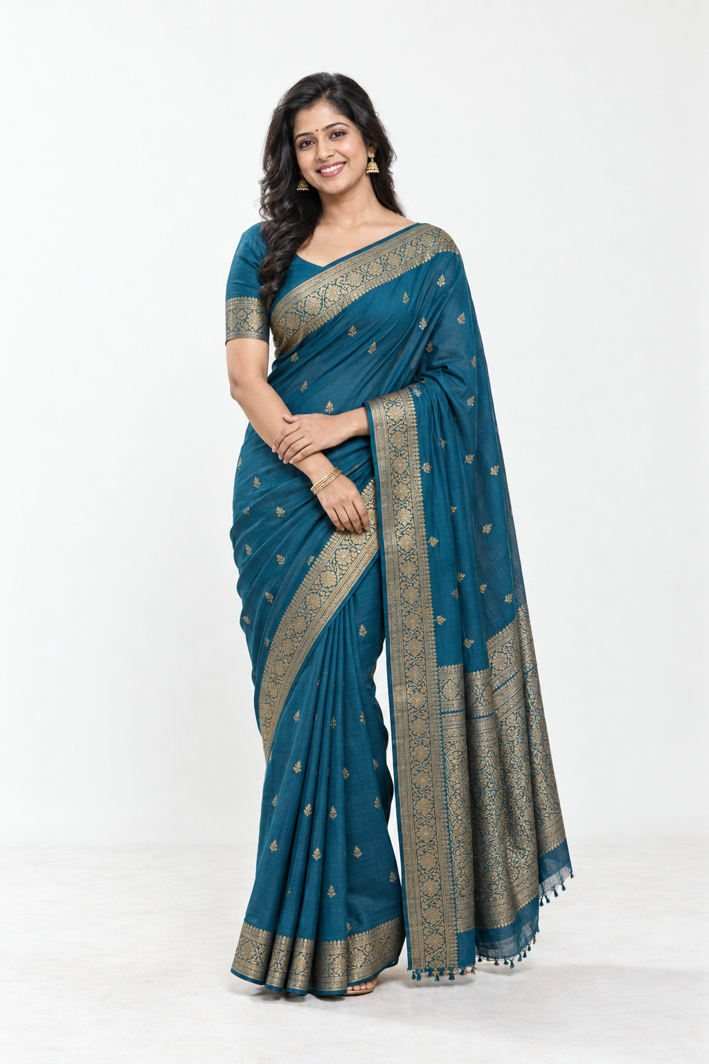 Smiling model in a peacock teal saree with an antique gold border, shown in full length